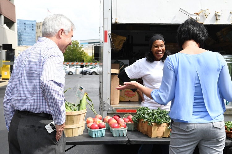 Allison Dehonney of Urban Fruits & Veggies talks with Bruce  Morlok, a temporary Blue Cross Blue Shield worker, and Janene  Kosnikowski, a Blue Cross Blue Shield employee resources employee,  during her pop-up market at BCBS on Sept. 9, 2017.